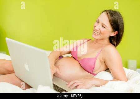 Schwangere Frau mit Laptop im Bett - schwangere Frau mit Laptop Stockfoto