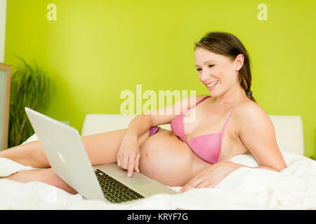Schwangere Frau mit Laptop im Bett - schwangere Frau mit Laptop Stockfoto
