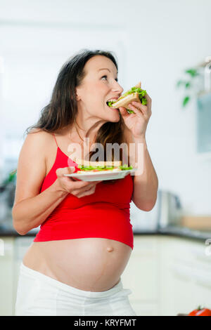 Schwangere Frau isst ein Sandwich - schwangere Frau isst ein Sandwich Stockfoto