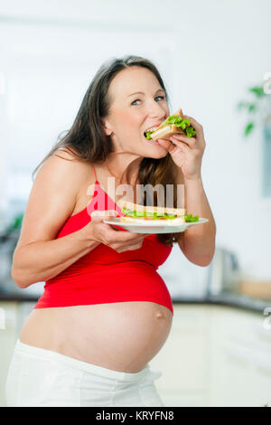 Schwangere Frau isst ein Sandwich - schwangere Frau isst ein Sandwich Stockfoto