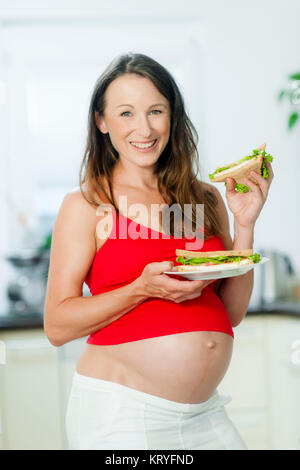 Schwangere Frau isst ein Sandwich - schwangere Frau isst ein Sandwich Stockfoto