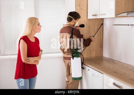 Männliche Arbeiter Sprühen von Insektiziden in der Küche Stockfoto