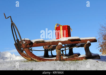 weihnachtsschlitten im Schnee. weihnachtsschlitten mit Geschenk im Schnee Stockfoto