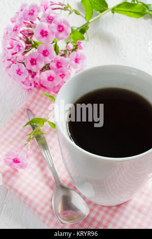 Morgens Kaffee oder eine Tasse Kaffee mit rosa Blüten. Stockfoto