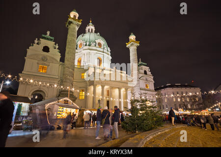 Beliebte Christkindlmarkt am Karlsplatz mit Masse von Touristen und Menschen in festlicher Weihnachtsstimmung. Karlskirche (St. Charles's Church) im Hintergrund Stockfoto