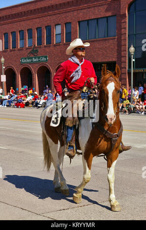 Cody, Wyoming, USA - Cowboy mit leuchtend roten shirt Reiten auf der Independence Day Parade Stockfoto