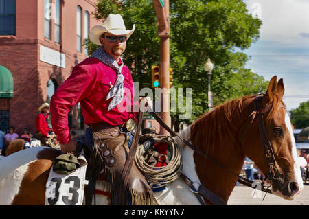 Cody, Wyoming, USA - Cowboy mit leuchtend roten shirt Reiten auf der Independence Day Parade Stockfoto