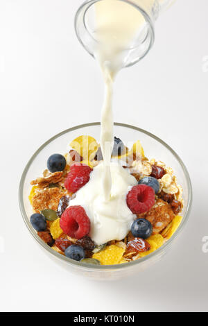 Milch in Frühstückscerealien gießen Stockfoto