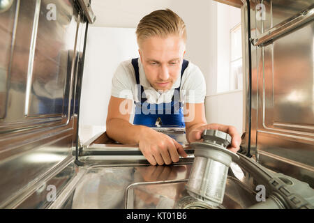 Mann In insgesamt Reparatur Spülmaschine Stockfoto