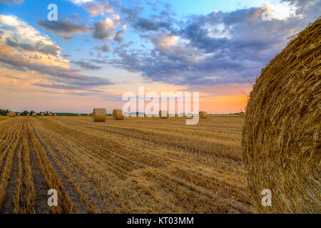 Sonnenuntergang über Feld-Hof mit Heuballen Stockfoto
