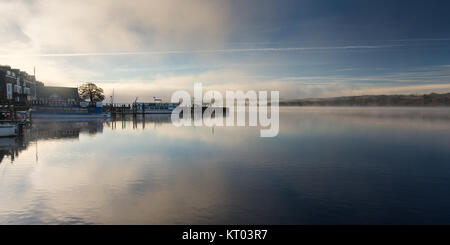 Nebel steigt aus den ruhigen Gewässern des Windermere Lake am Waterhead Pier, neben Ambleside Youth Hostel, im englischen Lake District National Park. Stockfoto