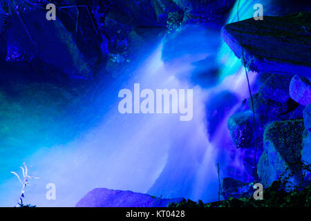 Mit Flutlicht beleuchteten Wasserfall bei RHS Gärten Harlow Carr - Glow Winter Illuminationen, Harrogate, North Yorkshire, England, UK. Stockfoto