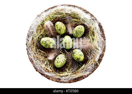 Dekorative Ostereier im Korb mit Heu und Perlhühner Federn Stockfoto