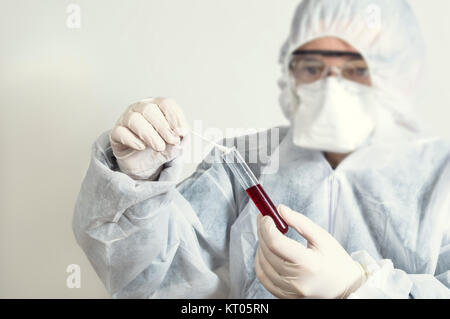 Wissenschaftler Schutzanzug tragen und ein Reagenzglas zu untersuchen. Stockfoto