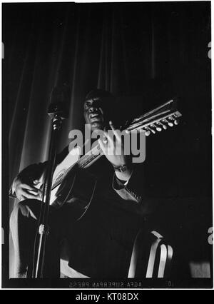 Dieses Porträt von Leadbelly, das zwischen 1938 und 1948 im National Press Club in Washington, D.C. aufgenommen wurde, fängt den berühmten amerikanischen Folk- und Bluesmusiker ein. Leadbelly, bekannt für seine kraftvolle Gesangs- und Songkomposition, hatte einen bedeutenden Einfluss auf die amerikanische Musikgeschichte. Stockfoto