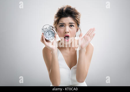 Porträt der schönen jungen Frau hält einen Wecker Stockfoto