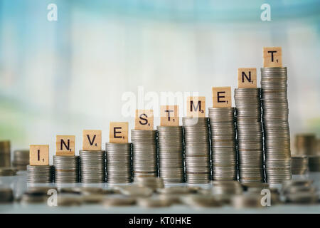 Stzck von Münzen mit Holz- Scrabble Buchstaben Stockfoto