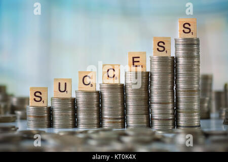 Stzck von Münzen mit Holz- Scrabble Buchstaben Stockfoto