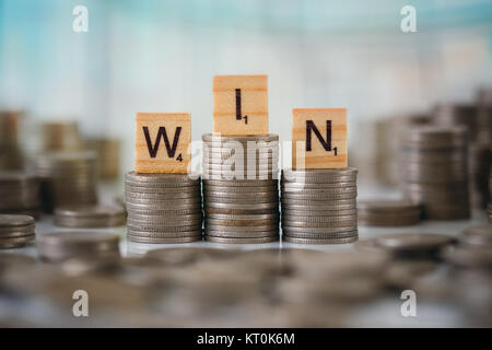 Stzck von Münzen mit Holz- Scrabble Buchstaben Stockfoto