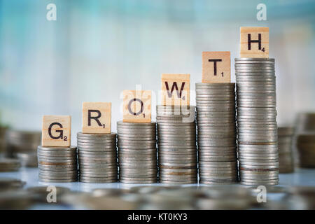 Stzck von Münzen mit Holz- Scrabble Buchstaben Stockfoto