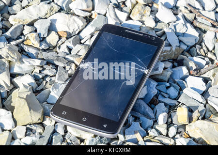 Frustriert Telefon auf den Felsen. Glas zerbricht auf Felsen auf einer sma Stockfoto