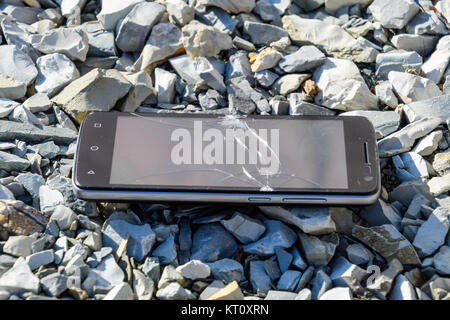 Frustriert Telefon auf den Felsen. Glas zerbricht auf Felsen auf einer sma Stockfoto