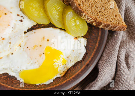 Spiegeleier mit marinierten Gurken und Roggenbrot. Stockfoto