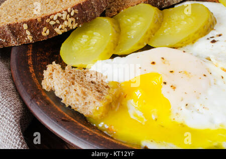 Spiegeleier mit marinierten Gurken und Roggenbrot. Stockfoto