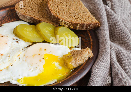 Spiegeleier mit marinierten Gurken und Roggenbrot. Stockfoto