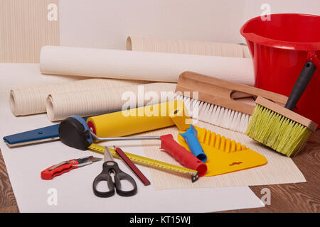 Rollen von Tapeten und verschiedene Werkzeuge zum Tapezieren. Stockfoto