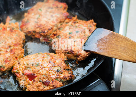 hausgemachte Frikadellen mit Gemüse in der Pfanne auf Keramik Herd kochen Stockfoto