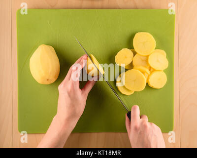 Hände, die Kartoffel auf Schneiden verwendet Kunststoffplatte Stockfoto