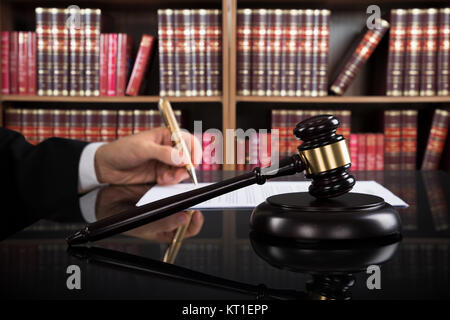 Nahaufnahme der Richter Schreiben auf Papier und Hammer am Schreibtisch Stockfoto