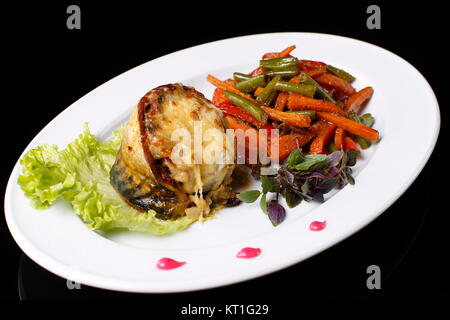 Auf einem weißen Teller Fisch frittierte Makrele in Käse, gekochtes Gemüse. Grüne Bohnen, Möhren, Basilikum, Salat., auf einem schwarzen Hintergrund. Gebratene Makrele Stockfoto