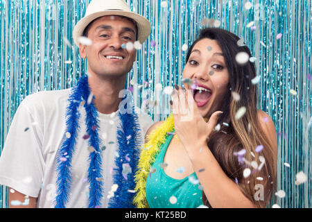 Brasilianische Paar ist zu einem Karneval Party. Er ist schwarz und hat Sie asiatische Abstammung. Farben: Blau, Grün und Gelb. Die Frau ist mit dem Regen der Co ekstatisch Stockfoto