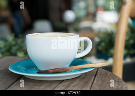 Kaffeetasse mit Löffel aus Holz auf Tisch im Café an der Außenseite Stockfoto