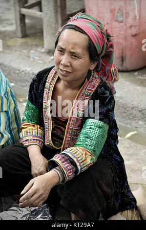 Tribeswoman mit traditionellen Kleid bei Meo Vac Markt sitzend, Provinz Ha Giang, Vietnam Stockfoto