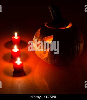 Glühend Halloween Kürbis mit brennenden Kerzen und Reflexion Stockfoto