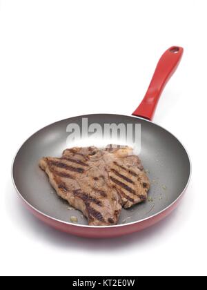 Ein T-Bone Steak in der Pfanne vor einem weißen Hintergrund isoliert Stockfoto