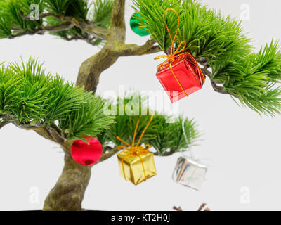 Weihnachtsdekoration oder Ornament hängen auf künstliche Bonsai Baum aus Rot, Gold und Silber Geschenkbox auf weißem Hintergrund mit Konzept der Stockfoto