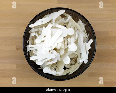 Ein Papierkorb mit Menschen Ausschnitte isoliert auf einem Holzfußboden Stockfoto