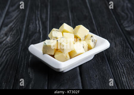 Kleine quadratische Stücke von Blauschimmelkäse. Käse mit Schimmel. Stockfoto