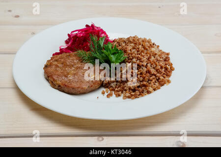 Teil von gebratenem Rindfleisch Schnitzel, gekochten Buchweizen und eingelegtes Rotkohl Stockfoto