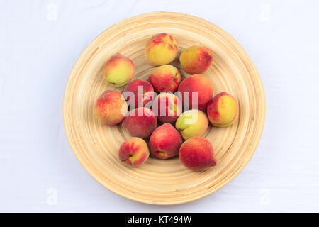 Ein hölzernes Schüsselchen von gemischten Früchten auf einem hölzernen Hintergrund, Banane, Kirschen, Pfirsiche Stockfoto
