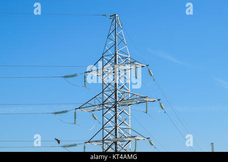 Unterstützt Hochspannungsleitungen gegen den blauen Himmel Stockfoto