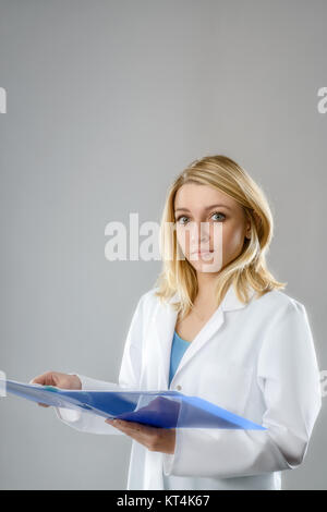 Porträt einer junge energische Wissenschaftlerin, Tech oder Student der Medizin mit Noten in blau Ordner auf grauem Hintergrund. Platz für Ihren Text. Stockfoto