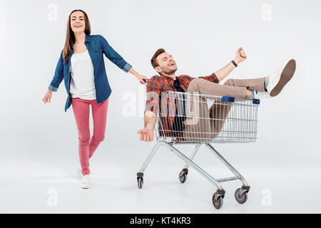 Lächelnde junge Frau, die glücklich in den Warenkorb Stockfoto