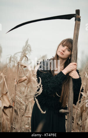 Schöne geheimnisvolle mystische Mädchen mit langen Haaren in schwarzem Kleid Holding ein Zopf in den dunklen Wald auf dem Weg. Mystische hübsches Mädchen in allen schwarze Kleidung mit Geflecht stehen in dunklen mystischen Wald Stockfoto