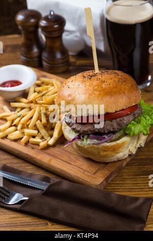 Hot Burger auf Holzbrett mit dunklem Bier Stockfoto