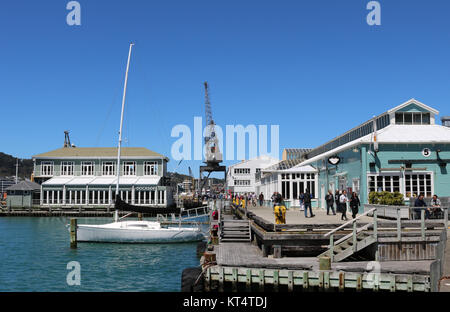 Verschiedene Leute, Touristen und Einheimische, Wandern am Wasser vorbei an Lagerhallen an der Queens Wharf in den Hafen von Wellington, Nordinsel, Neuseeland Stockfoto